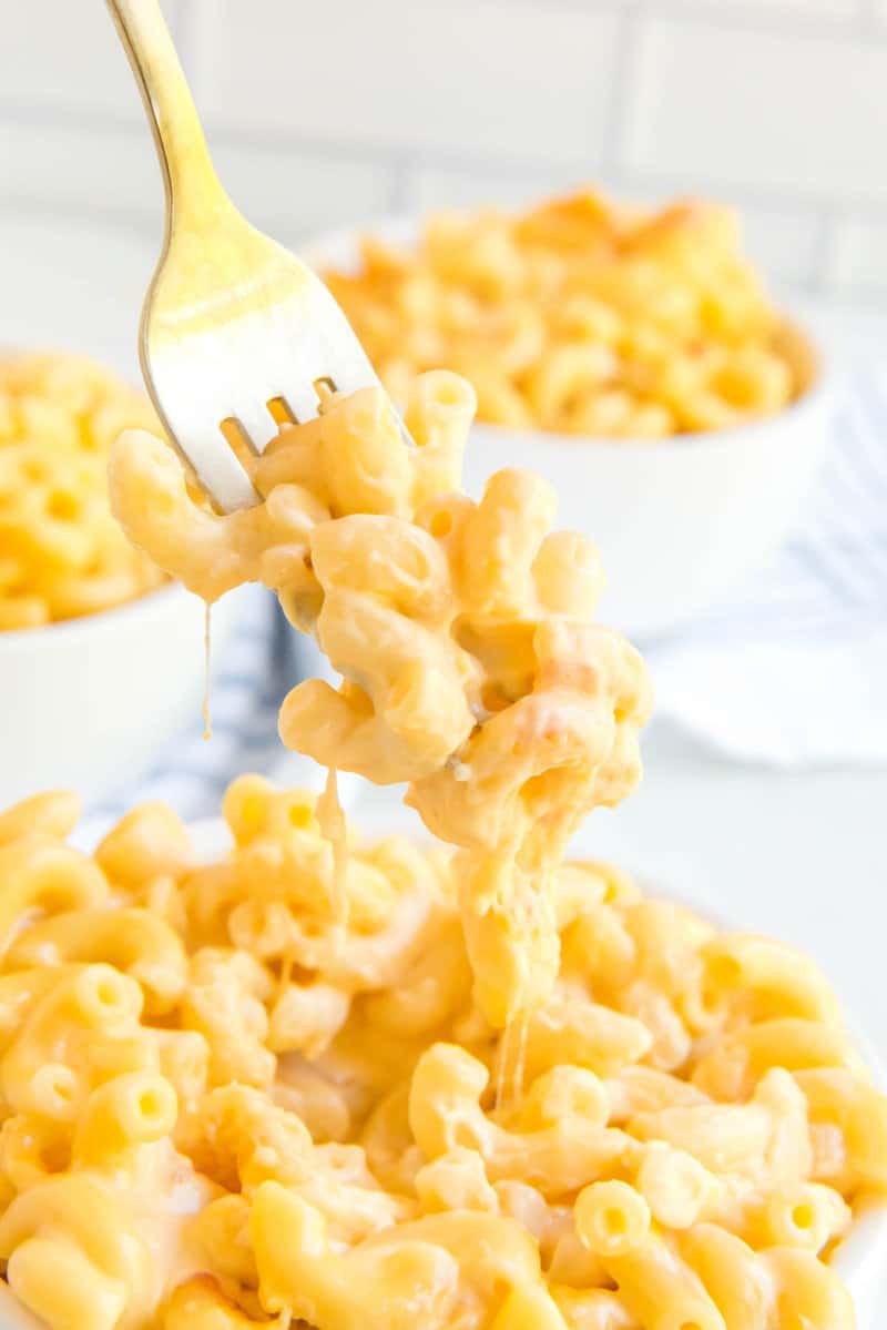 Copycat Chick Fil A mac and cheese on a fork held over a bowl of it.