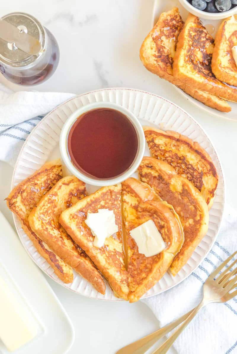 Overhead view of copycat Cracker Barrel French toast and a bowl of syrup on a plate.