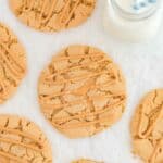 Overhead view of copycat Crumbl ultimate peanut butter cookies and a glass of milk.