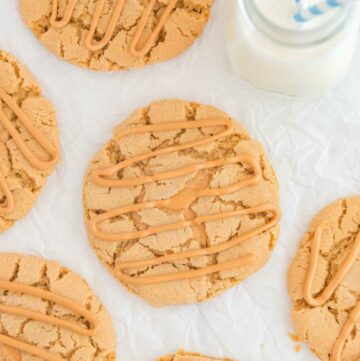 Overhead view of copycat Crumbl ultimate peanut butter cookies and a glass of milk.