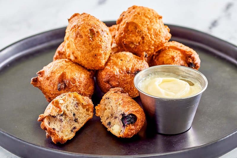 Copycat Denny's blueberry pancake puppies and a small cup of cheesecake dip.