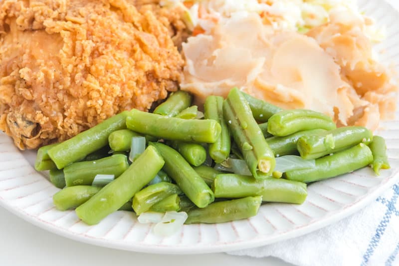 Copycat KFC green beans on a plate with fried chicken and mashed potatoes.