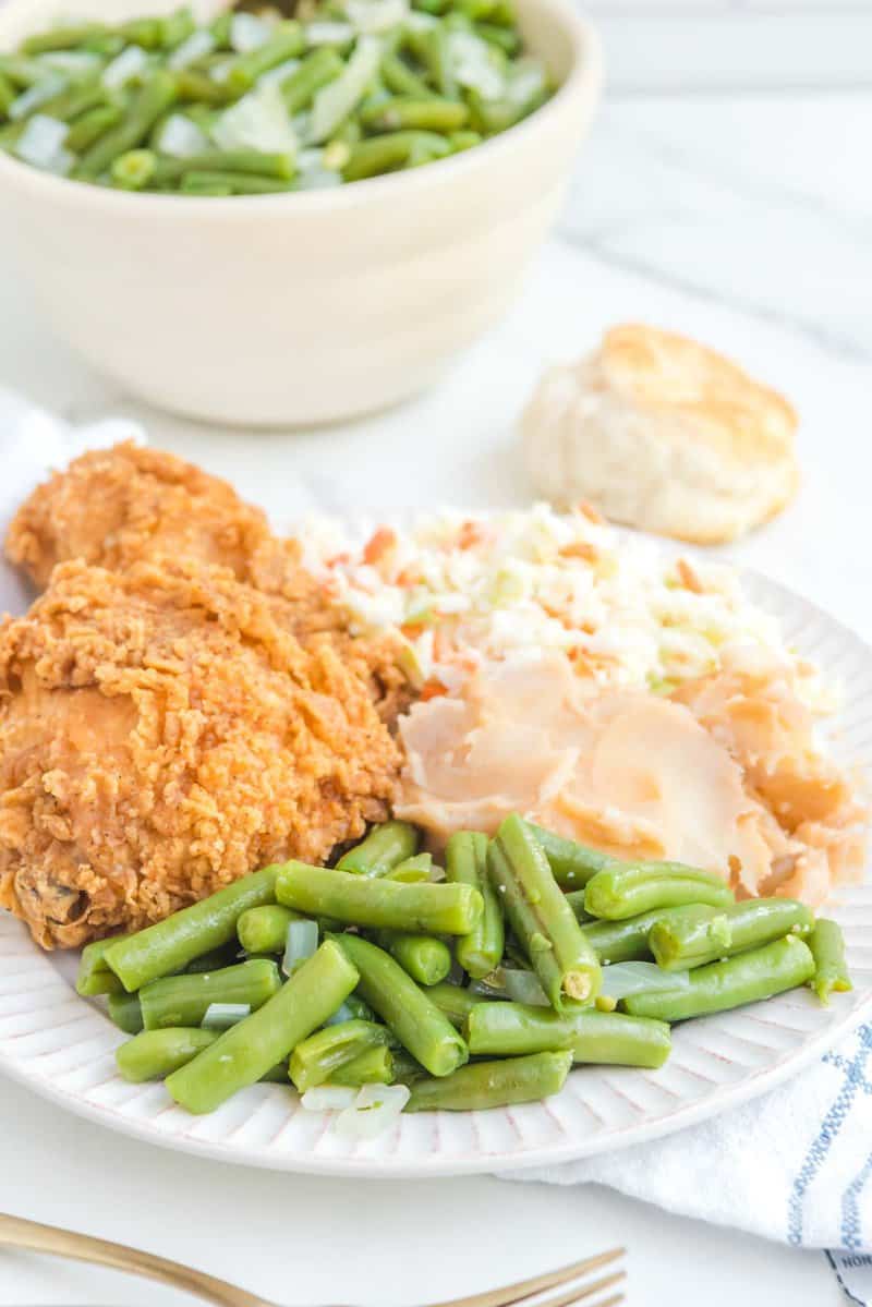 Copycat KFC greenish  beans connected  a sheet  with fried chicken, mashed potatoes, and cole slaw.