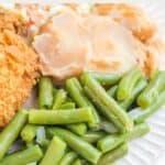 Homemade KFC green beans on a plate with mashed potatoes and fried chicken.