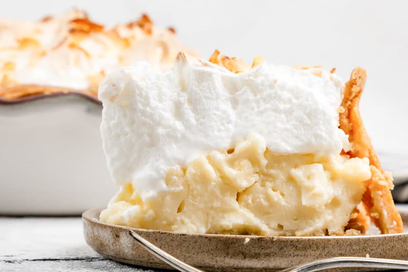 A slice of Luby's coconut meringue pie with the pie behind it.