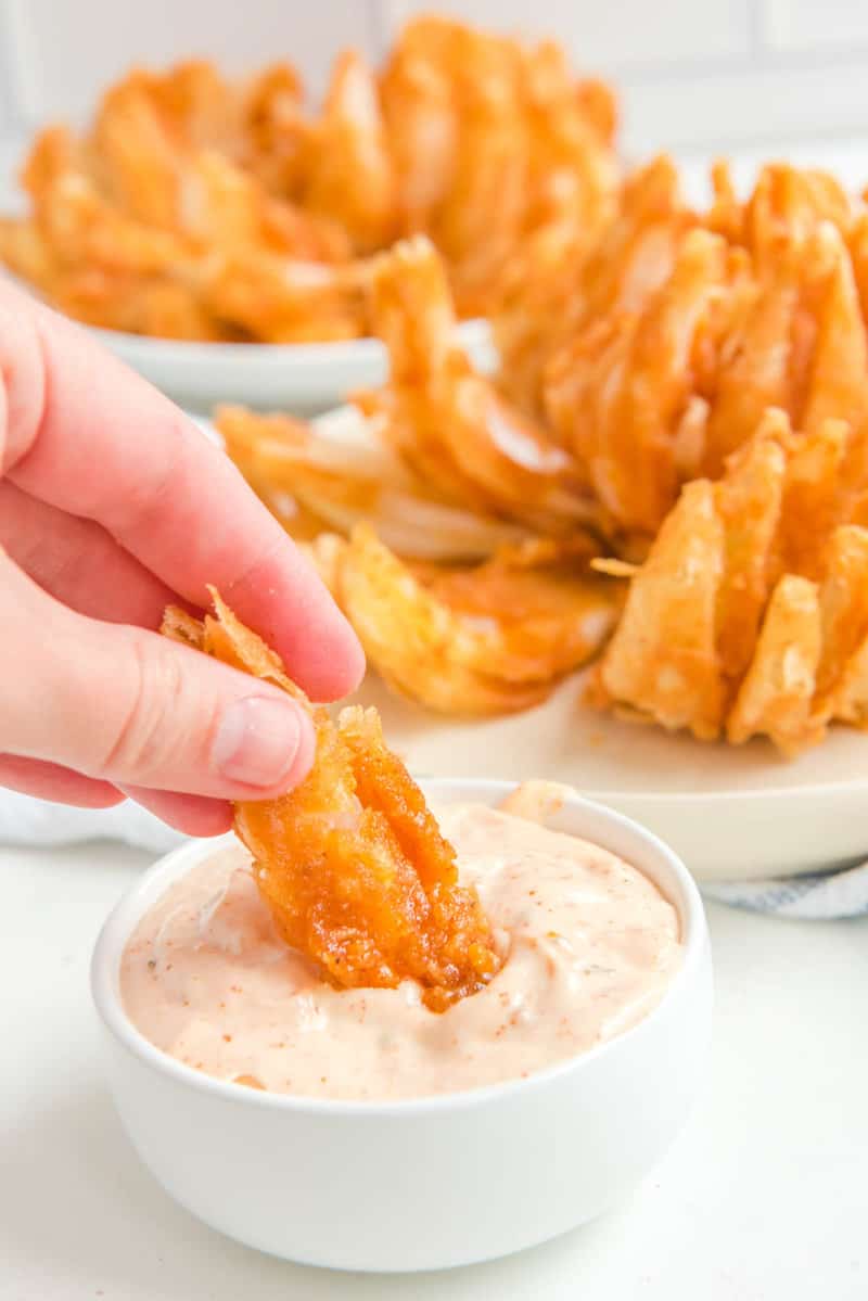 Dipping a blooming onion petal into sauce.