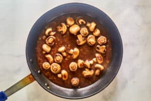 Sauteed mushrooms and red wine sauce in a skillet.