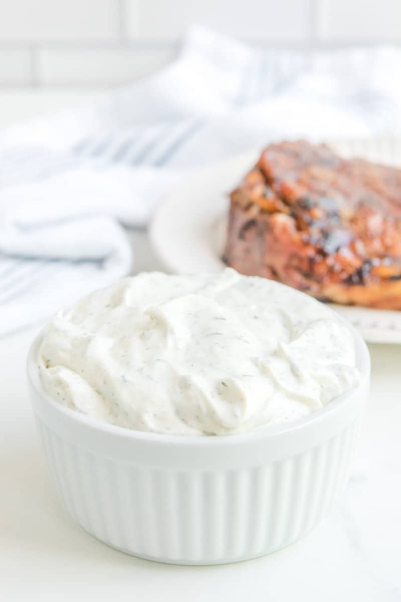 Copycat Outback tiger dill sauce in a bowl with a steak on a plate behind it.