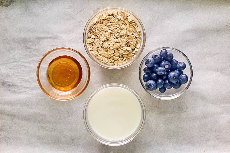 Overnight oats ingredients in bowls on parchment paper.