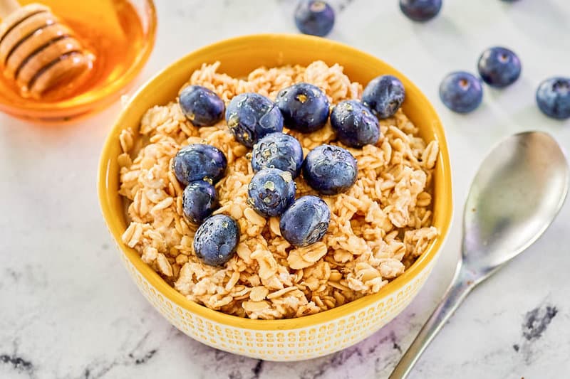 Overnight oats topped with blueberries and honey in a bowl.