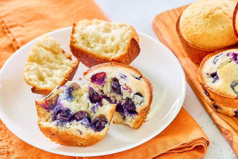 Homemade basal  blueberry and plain saccharine  muffins connected  a plate.