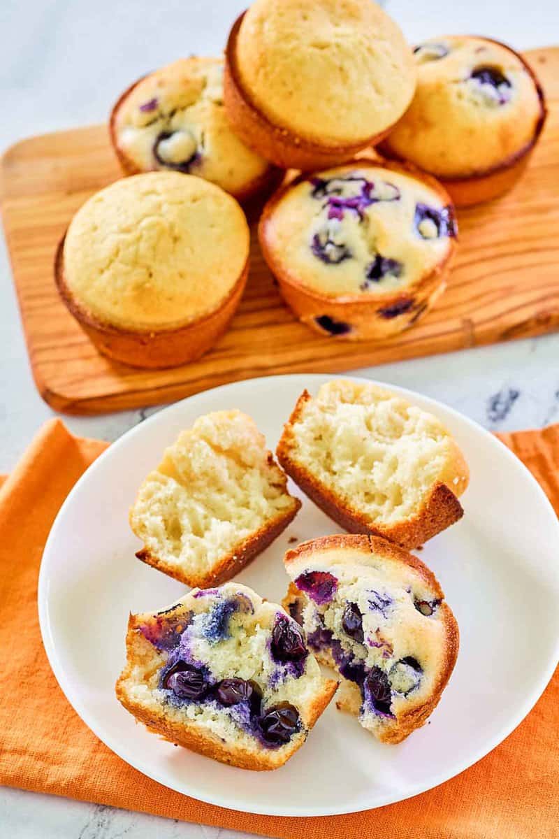 Homemade blueberry and plain sweet muffins on a plate and on a wood board.