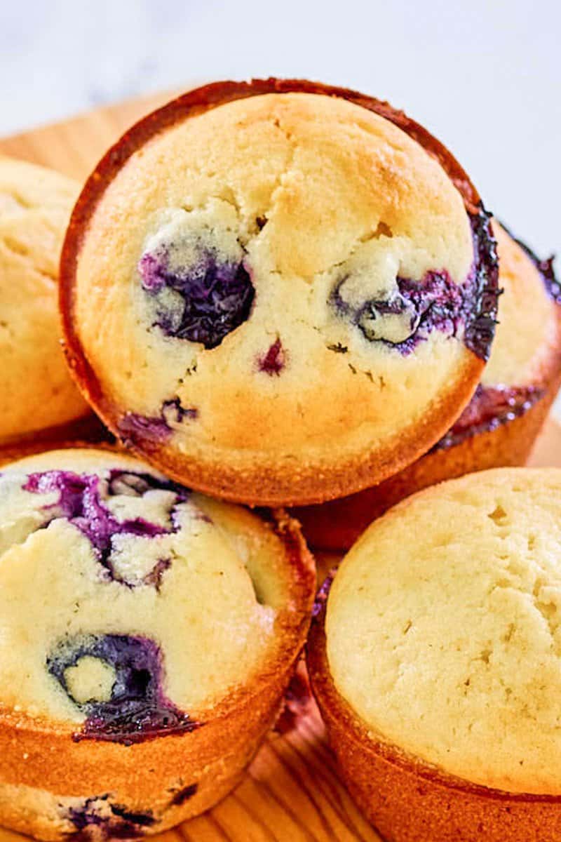 Blueberry and plain saccharine  muffins connected  a wood   board.