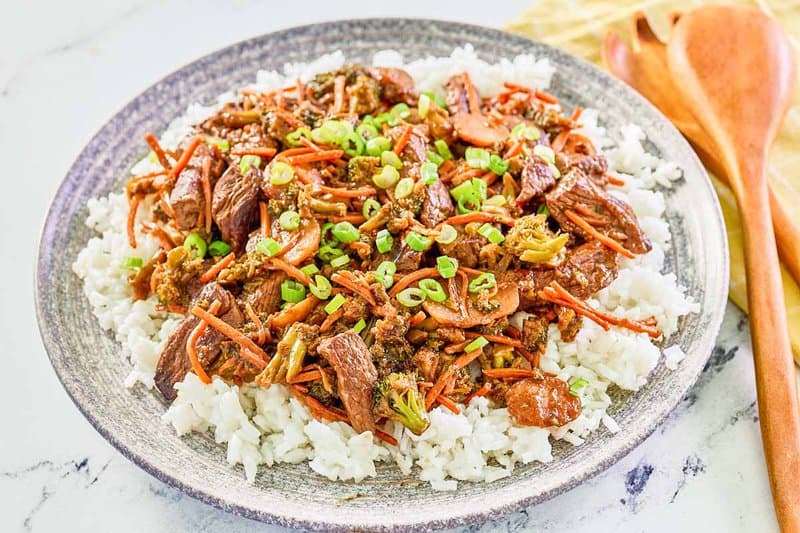 Teriyaki beef stir fry over rice on a large plate.