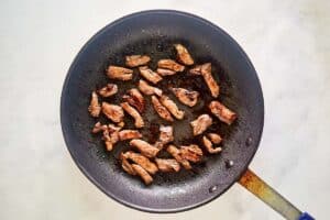 Stir fried beef strips in a skillet.