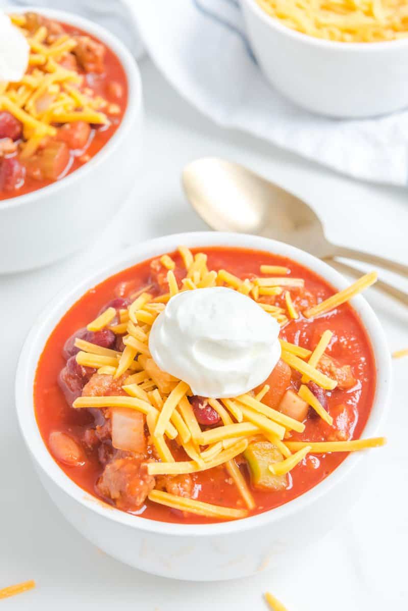 Bowl of copycat Wendy's chili topped with shredded cheese and sour cream.