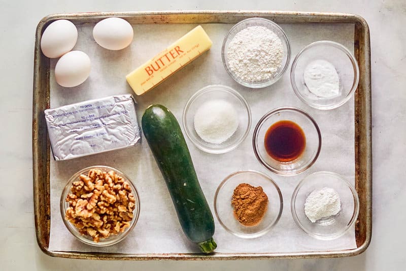 Ingredients for zucchini nut bread with cream cheese frosting on a tray.