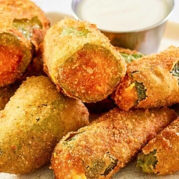 Cheddar cheese jalapeno poppers and a cup of dipping sauce on a plate.