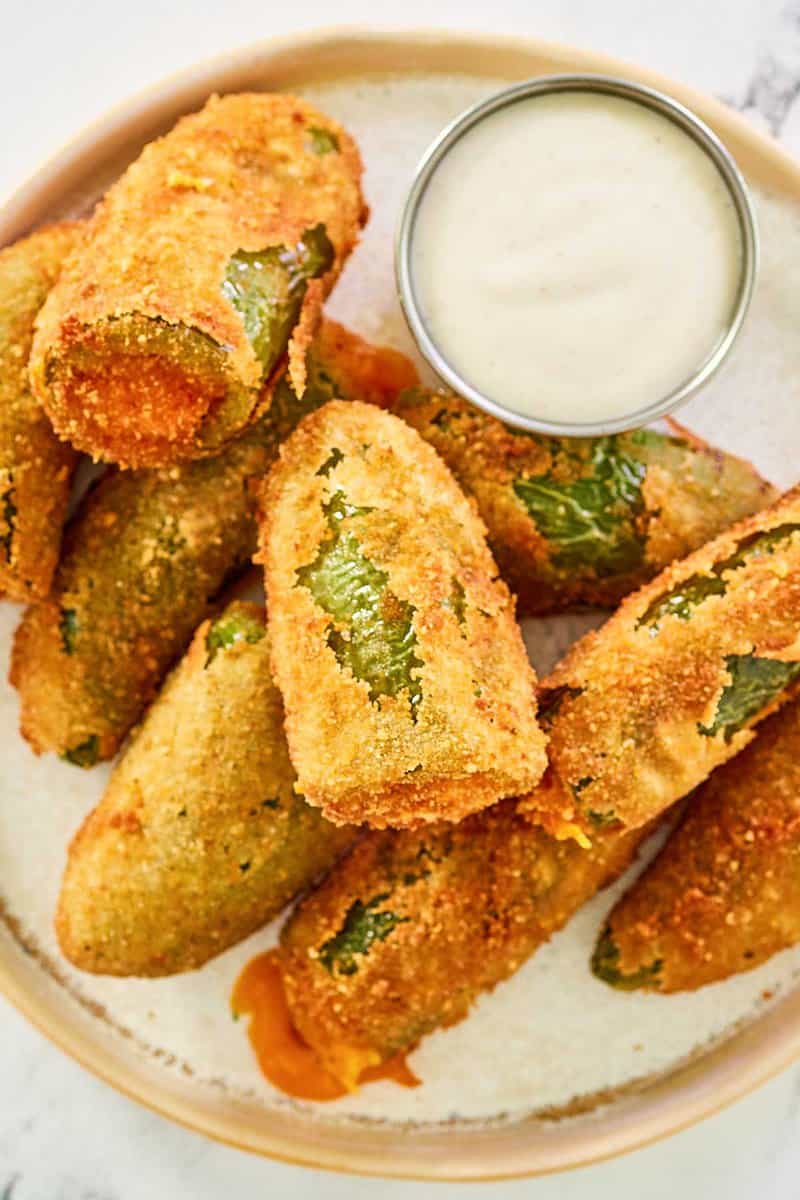 Overhead view of cheddar cheese jalapeno poppers and a small cup of dipping sauce.