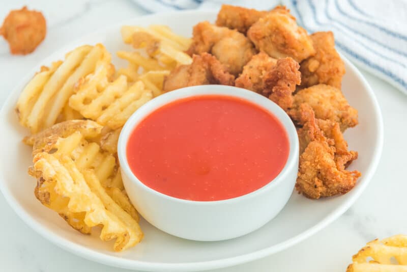 Copycat Chick Fil A Polynesian sauce, chicken nuggets, and waffle fries on a plate.