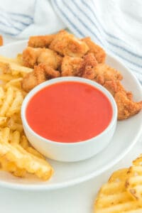 Copycat Chick Fil A Polynesian sauce in a bowl on a plate with chicken nuggets and waffle fries.