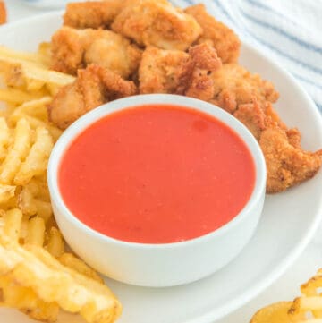 Copycat Chick Fil A Polynesian sauce in a bowl on a plate with chicken nuggets and waffle fries.