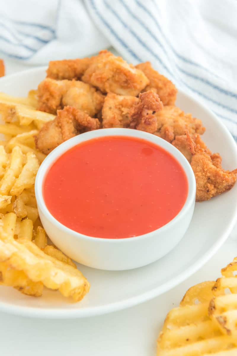 Copycat Chick Fil A Polynesian sauce in a bowl on a plate with chicken nuggets and waffle fries.