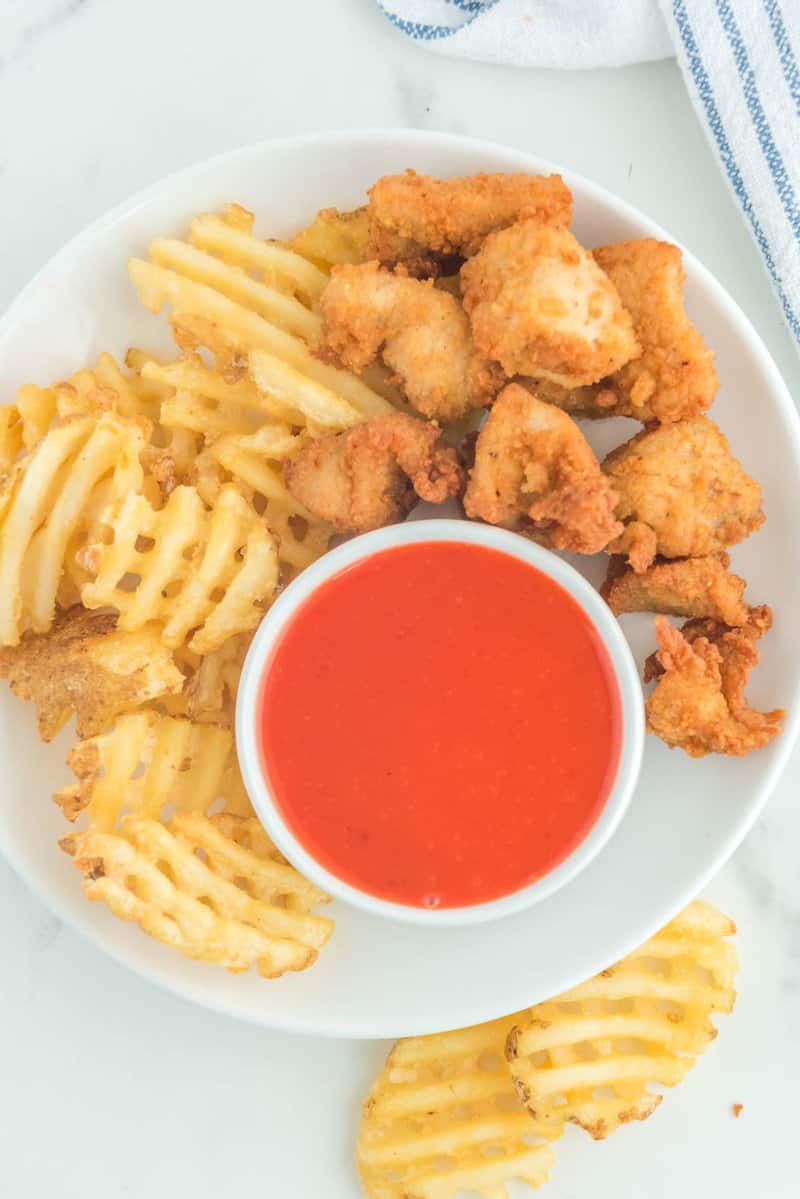 Overhead view of copycat Chick Fil A Polynesian sauce on a plate with chicken nuggets and waffle fries.