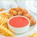 A bowl of homemade Chick Fil A Polynesian sauce, waffle fries, and chicken nuggets.