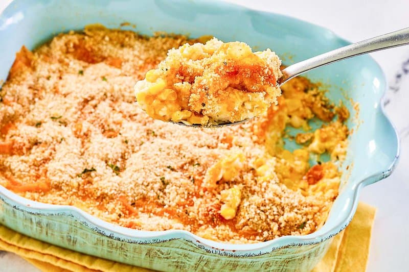 Creamed corn au gratin in a casserole dish and on a spoon.