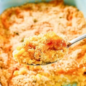 Creamed corn au gratin on a spoon and in a casserole dish.