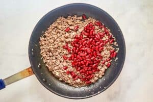 Cooked ground beef and red kidney beans in a skillet.