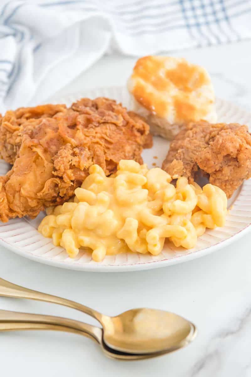 Copycat KFC mac and cheese, fried chicken, and a biscuit connected  a plate.