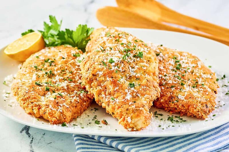 Copycat Luby's Italian chicken breast, parsley, and lemon on a white platter.