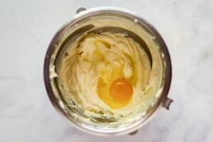 Adding egg to cheesecake filling mixture.