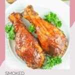 Two smoked chicken drumsticks and fresh parsley on a white platter.