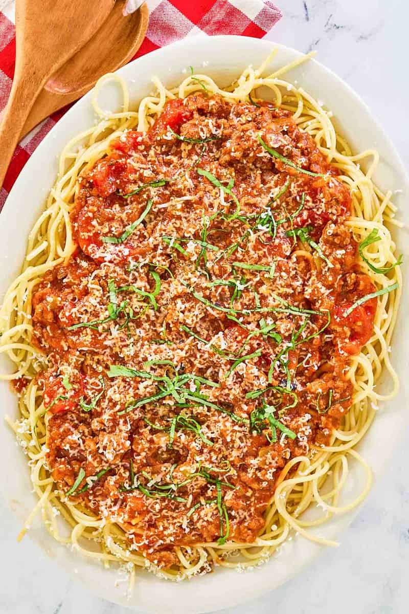 Overhead view of homemade spaghetti meat sauce over spaghetti pasta on a platter.