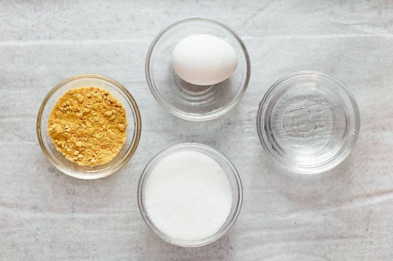 Homemade sweet hot mustard ingredients on in bowls on parchment paper.