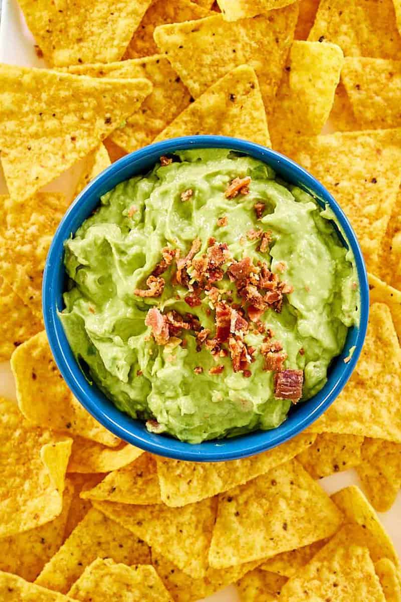 Overhead view of avocado dip and tortilla chips around it.