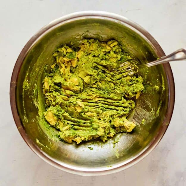 Mashed avocado and a fork in a bowl.