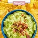 Overhead view of avocado dip topped with bacon bits in a bowl surrounded by tortilla chips.