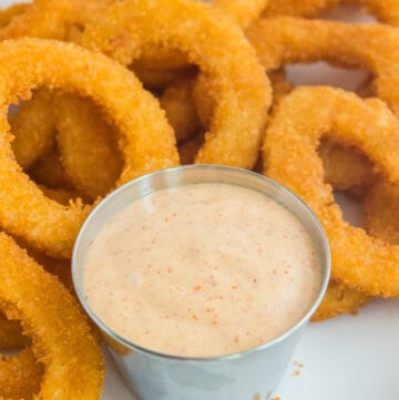 Copycat Burger King zesty sauce and onion rings on a plate.