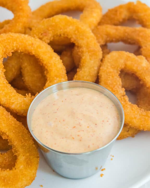 Copycat Burger King zesty sauce and onion rings on a plate.
