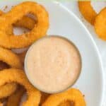Overhead view of homemade Burger King zesty sauce on a plate with onion rings.