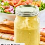 Homemade green onion salad dressing in a jar and a salad behind it.