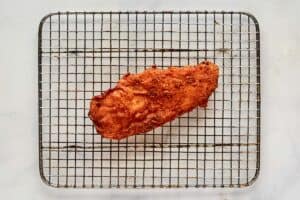 Fried chicken breast on a wire rack.
