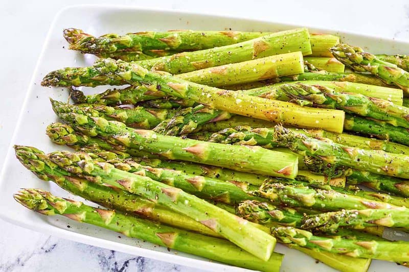 Oven roasted asparagus spears on a platter.