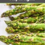 Tops of oven roasted asparagus on a white platter.