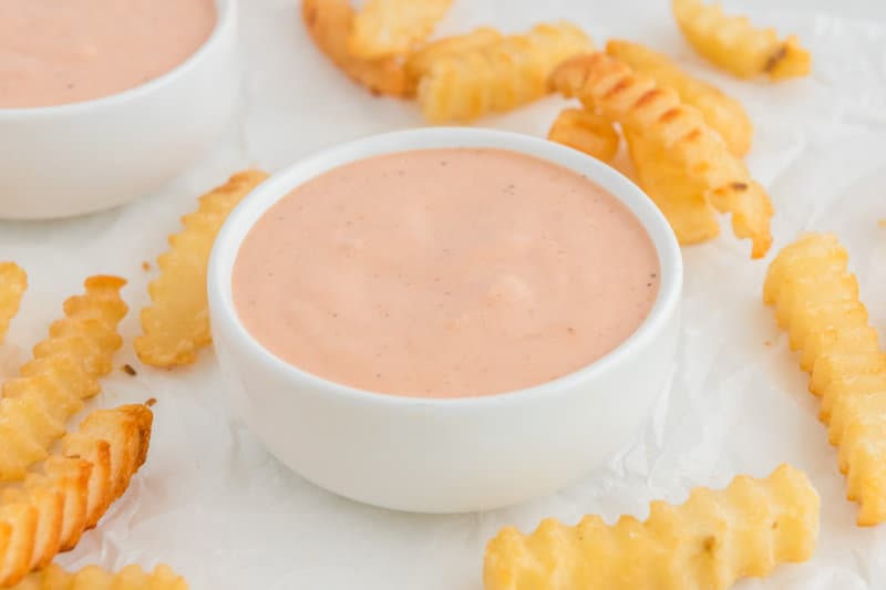 Copycat Raising Cane's sauce in bowls and crinkle-cut fries.