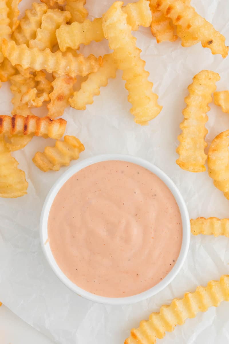 Overhead view of copycat Raising Cane's sauce and crinkle-cut French fries.